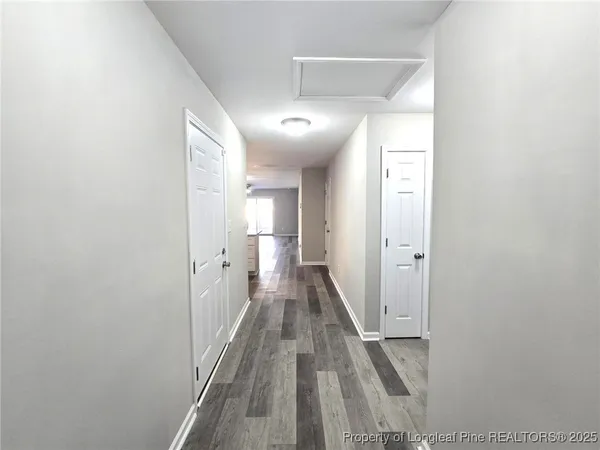 a view of a hallway with wooden floor and a bathroom