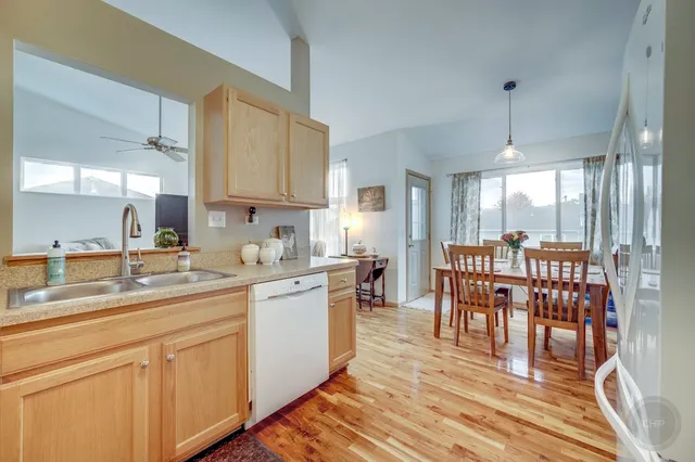 a kitchen with stainless steel appliances granite countertop a sink a stove a dining table and chairs