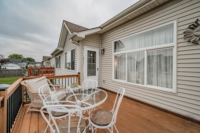 a view of a patio with table and chairs with wooden floor and fence