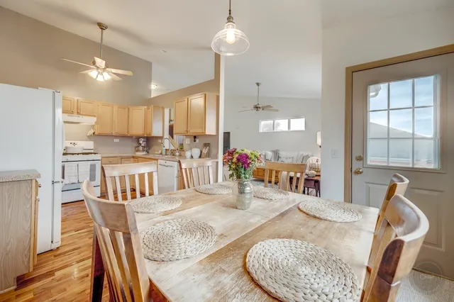 a kitchen with stainless steel appliances kitchen island granite countertop a table chairs in it and wooden floors