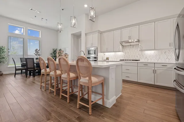 a large kitchen with cabinets chairs and wooden floor