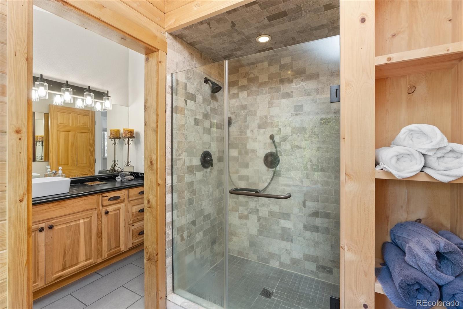 400 Upper Forest Road Idaho Springs, CO 80452 - Photo 10 of 20 a bathroom with a granite countertop shower a sink and a mirror