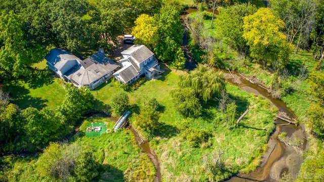 an aerial view of residential house with outdoor space and trees all around
