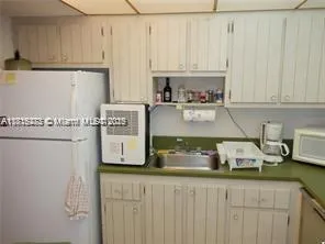 a kitchen with white cabinets and refrigerator