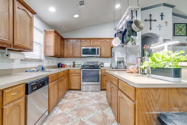 a kitchen with stainless steel appliances granite countertop a sink a stove and a wooden cabinets