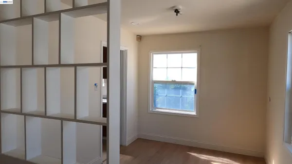 a view of an empty room with wooden floor and a window