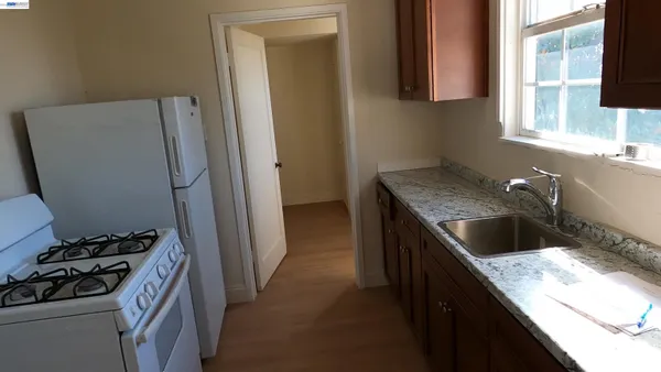 a kitchen with granite countertop a sink stove and refrigerator