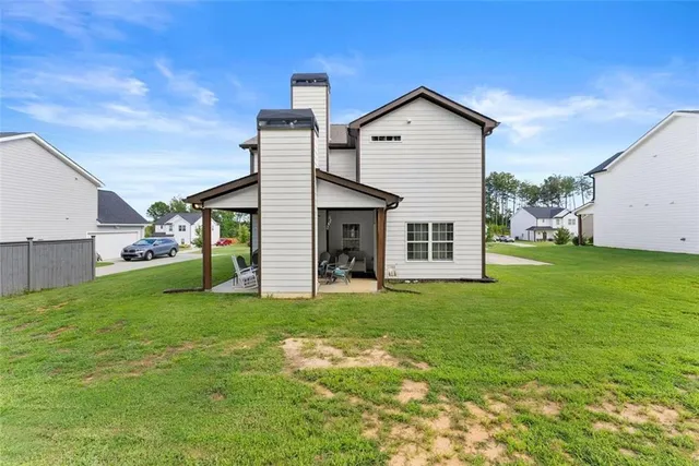 a view of a house with a big yard and large tree