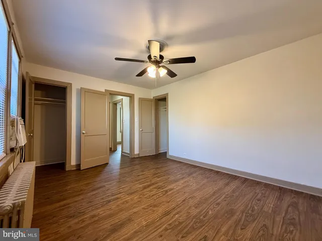 a view of an empty room with window and wooden floor