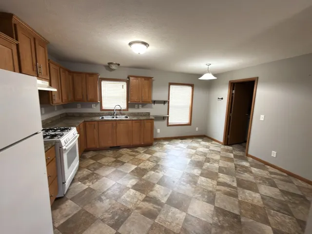 a kitchen with granite countertop a refrigerator and a stove top oven