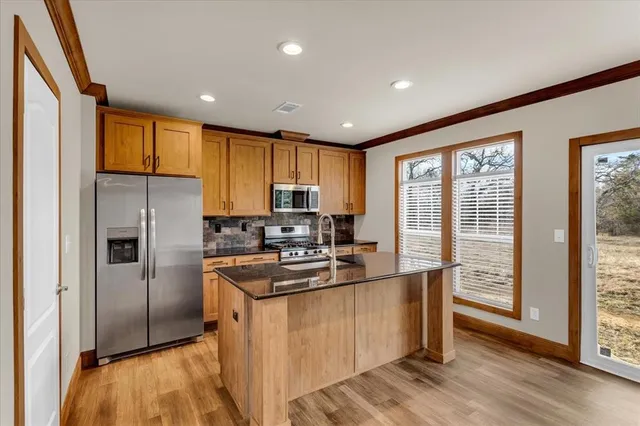 a kitchen with stainless steel appliances granite countertop a refrigerator a stove top oven a sink and cabinets