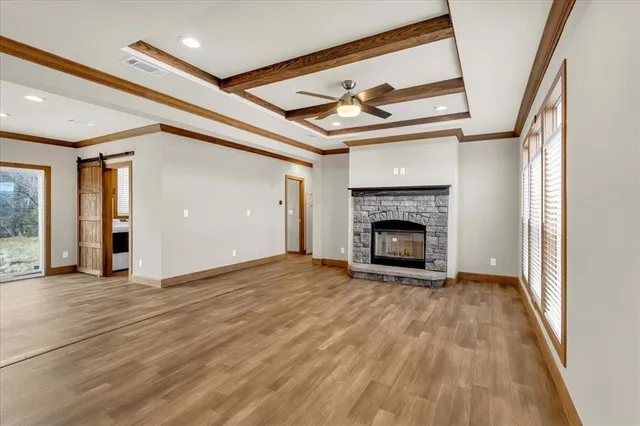 a view of an empty room with wooden floor fireplace and a window