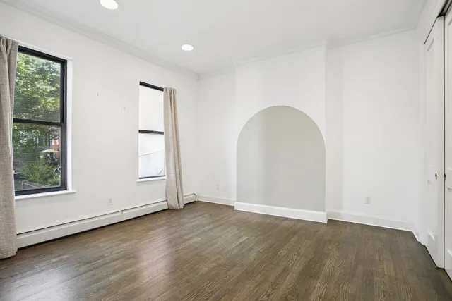 an empty room with wooden floor and windows