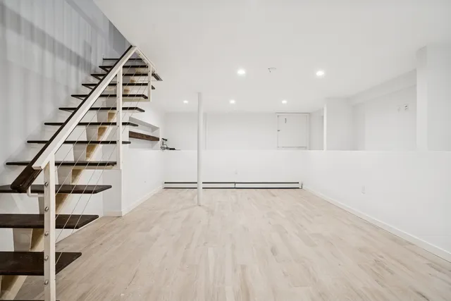 a view of an empty room with stairs and wooden floor