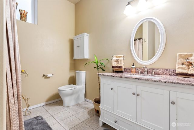 a bathroom with a granite countertop toilet a sink and a mirror