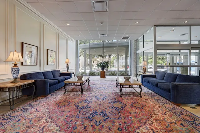 a living room with furniture a rug kitchen view and a large window