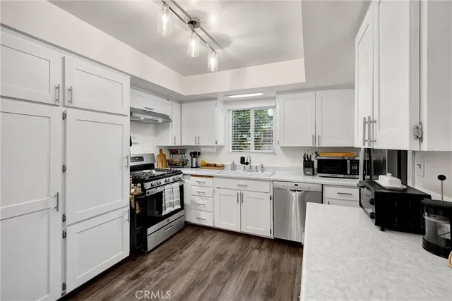 a kitchen with granite countertop white cabinets and white appliances