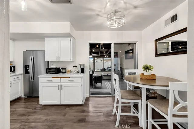 a kitchen with stainless steel appliances kitchen island granite countertop a table chairs and a refrigerator