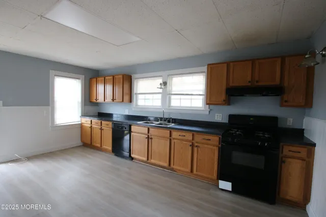 a kitchen with granite countertop a stove a sink wooden cabinets and a window