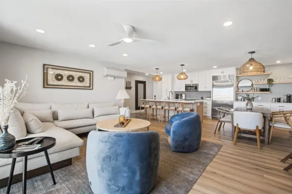 a living room with furniture kitchen view and a wooden floor