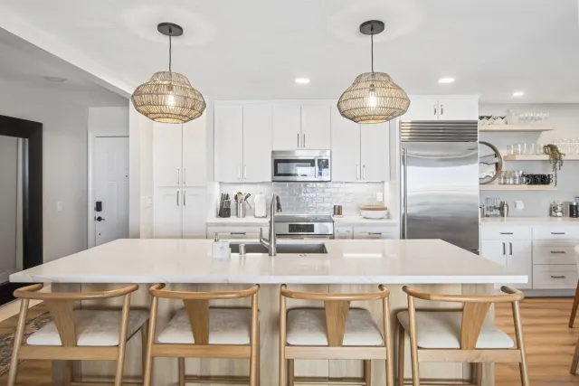 a kitchen with stainless steel appliances granite countertop a dining table chairs and white cabinets