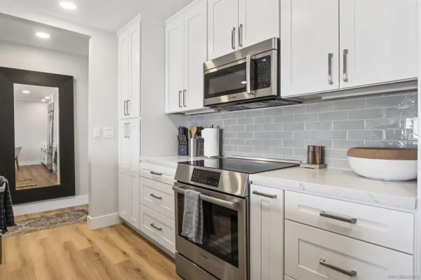 a kitchen with stainless steel appliances granite countertop white cabinets a microwave a sink and a counter