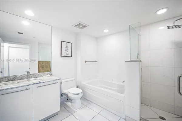 a bathroom with a granite countertop sink a toilet a large mirror and shower