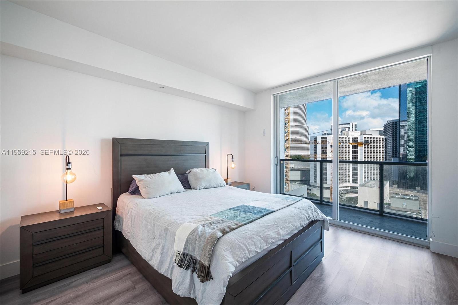 500 Brickell Avenue, Unit 1903 Miami, FL 33131 - Photo 8 of 18 a bedroom with a balcony a bed and wooden floor