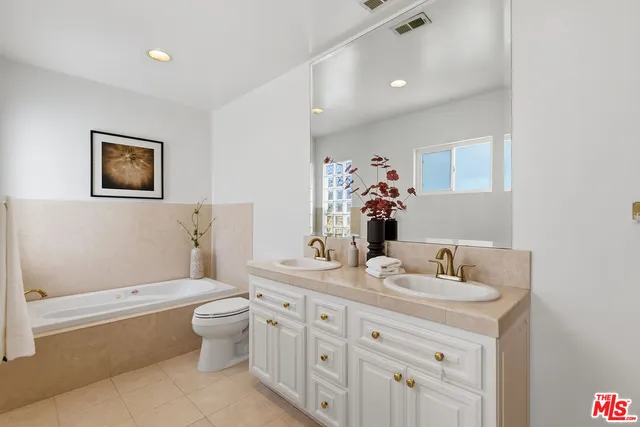 a bathroom with a double vanity sink toilet mirror and bathtub