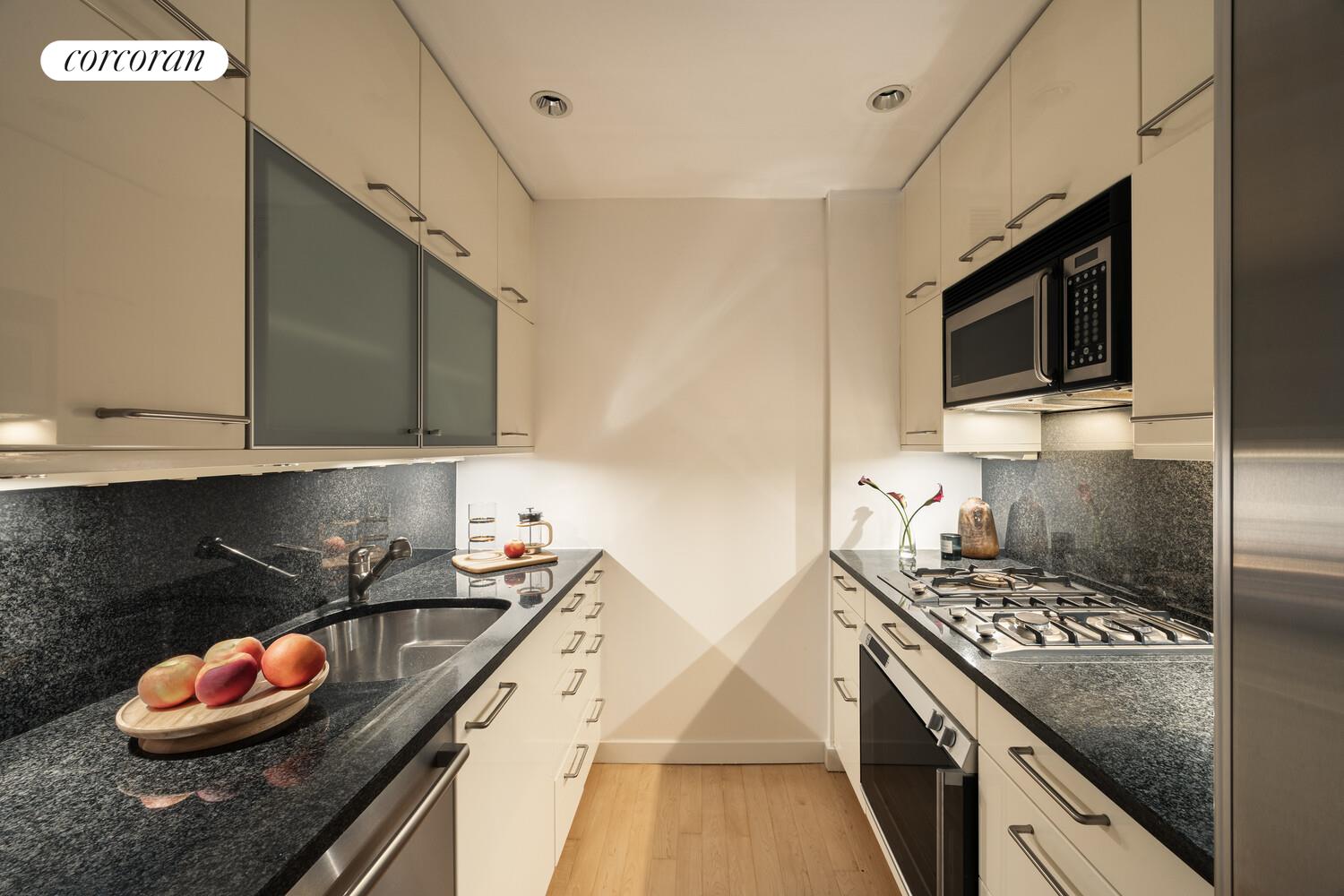 146 West 57th Street, Unit 58A Manhattan, NY 10019 - Photo 13 of 18 a kitchen with stainless steel appliances granite countertop a stove and a microwave