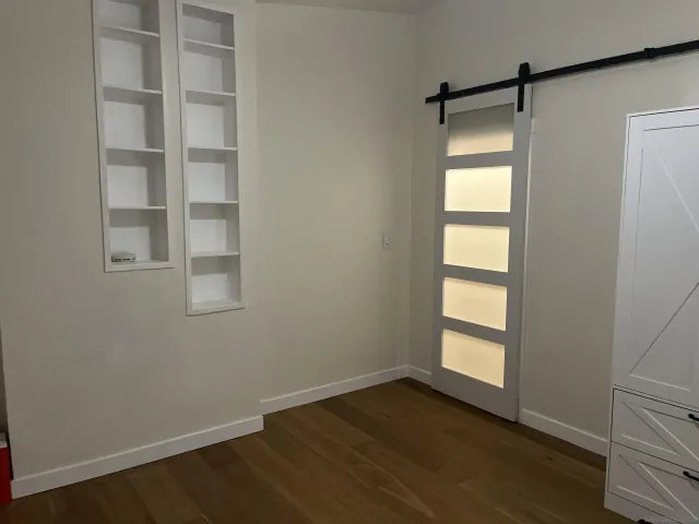 an empty room with wooden floor and windows