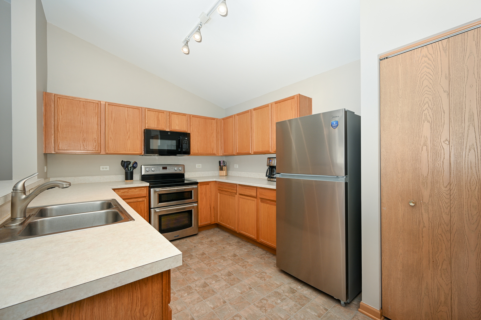 1425 McClure Road, Unit 1425 Aurora, IL 60505 - Photo 4 of 12 a kitchen with stainless steel appliances granite countertop a refrigerator stove and sink