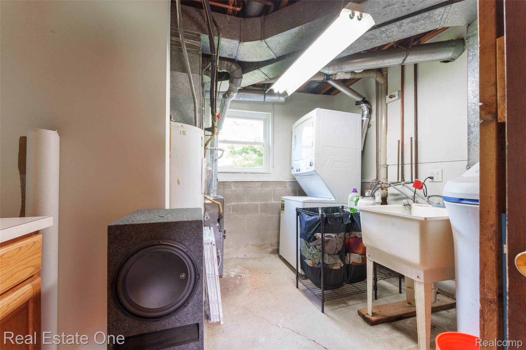 5130 Iosco Road Webberville, MI 48892 - Photo 29 of 39 Utility area featuring a laundry sink, stacked washer and dryer, and exposed ductwork