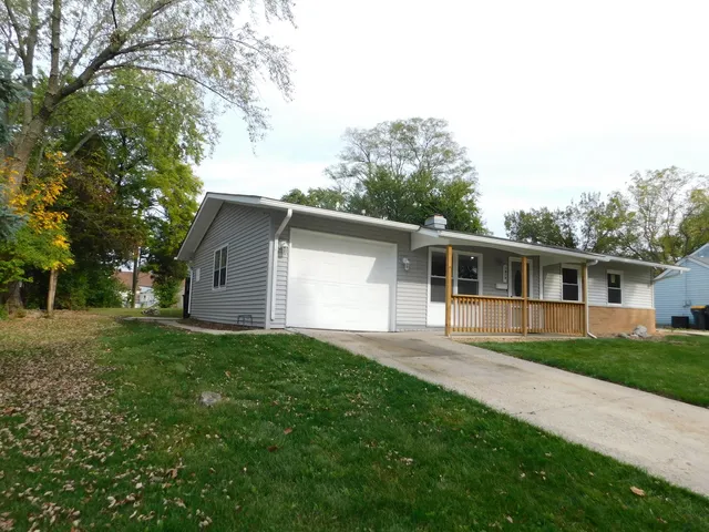 a front view of house with yard and trees in the background
