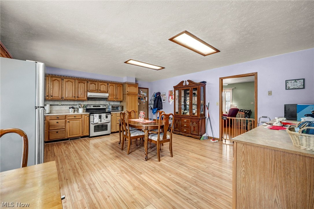 3830 Jerusalem Road Vermilion, OH 44089 - Photo 18 of 49 Kitchen featuring stainless steel appliances, light countertops, light wood-type flooring, wood finish cabinets, and a textured ceiling
