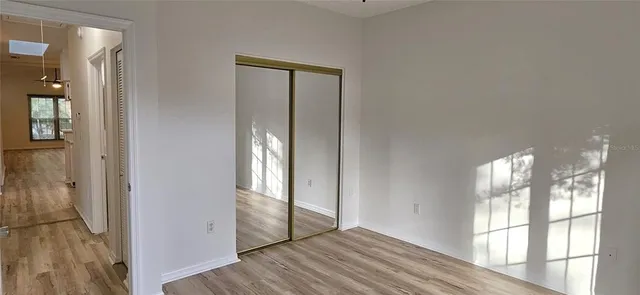 a view of empty room with wooden floor and fan