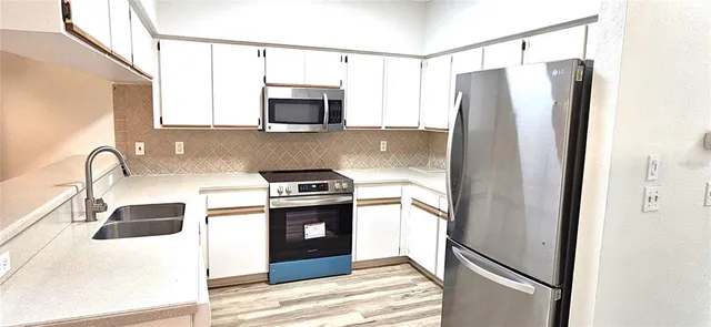 a kitchen with stainless steel appliances granite countertop a refrigerator a stove and a sink with wooden floor