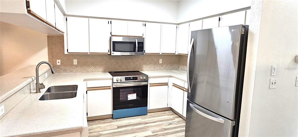 2736 Penzance Street Palm Harbor, FL 34684 - Photo 10 of 27 a kitchen with stainless steel appliances granite countertop a refrigerator a stove and a sink with wooden floor