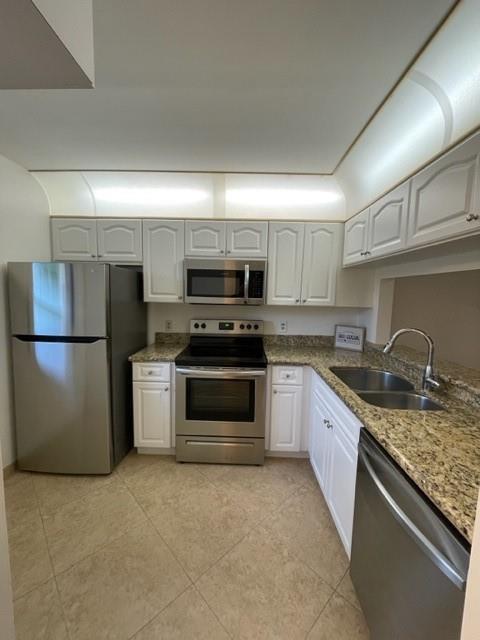 6760 Palmetto Circle South, Unit 102 Boca Raton, FL 33433 - Photo 1 of 5 a kitchen with granite countertop a refrigerator stove and microwave