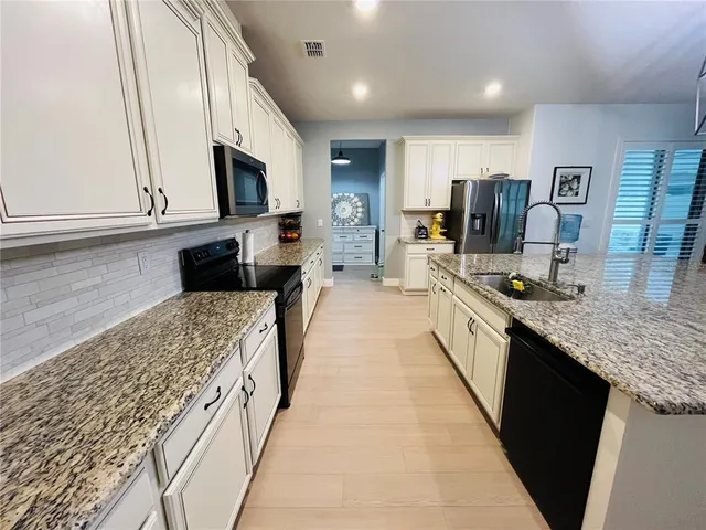 a large kitchen with stainless steel appliances kitchen island granite countertop a large counter top a stove and a sink