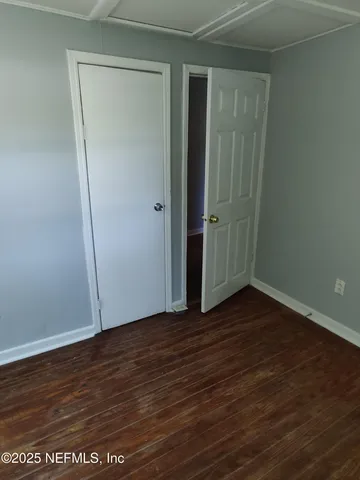 a view of an empty room with wooden floor and closet