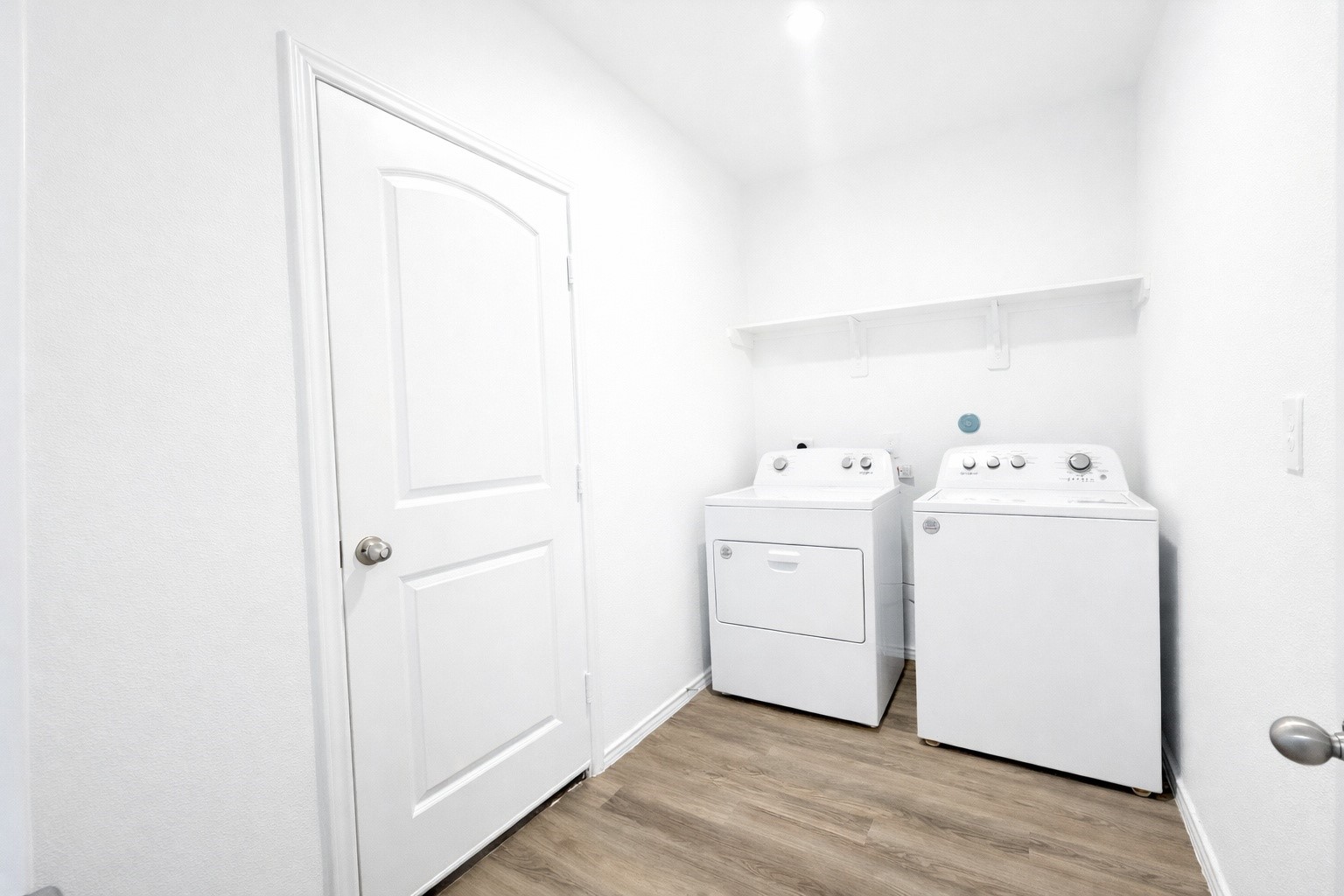 1739 Royal Rim Drive Houston, TX 77014 - Photo 12 of 20 Bright, functional laundry room with a washer and dryer, laminate flooring, and a white door. A shelf above provides additional storage space.