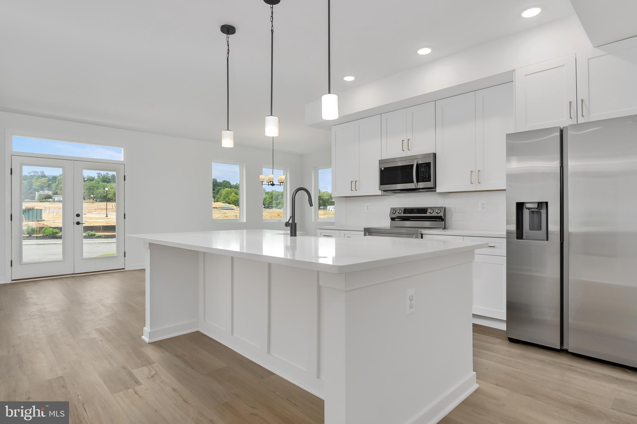 711 Iron Frg Road, Unit C Frederick, MD 21702 - Photo 6 of 15 a kitchen with stainless steel appliances a refrigerator a sink a stove a microwave and wooden floor