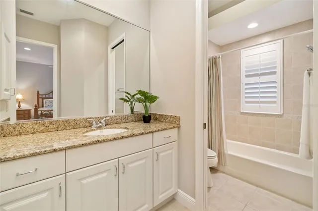 a bathroom with a granite countertop sink a toilet a mirror and shower