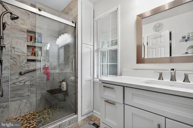 a bathroom with a sink shower and a mirror