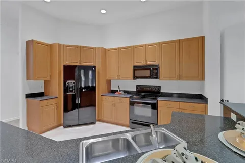 a kitchen with stainless steel appliances granite countertop a stove top oven a sink a dining table and chairs