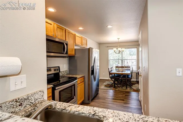 a kitchen with stainless steel appliances granite countertop a refrigerator stove top oven dining table and chairs