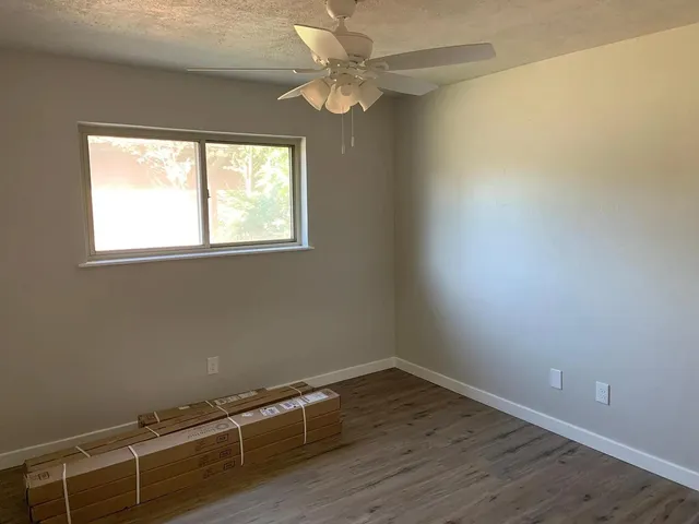 an empty room with a window and a fan