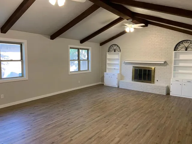 a view of empty room with wooden floor and fireplace