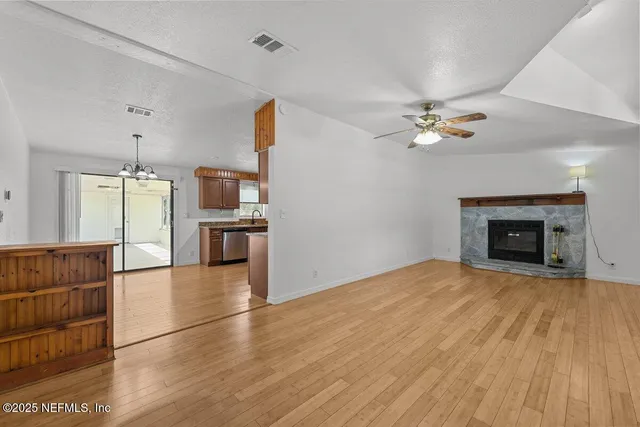 a view of empty room with kitchen and fireplace